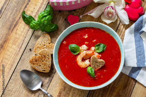 Homemade Valentine soup, festive food. Tomato soup puree gazpacho with tomatoes served seafood on a rustic wooden table. Copy space.