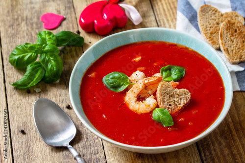 Homemade Valentine soup, festive food. Tomato soup puree gazpacho with tomatoes served seafood on a rustic wooden table.