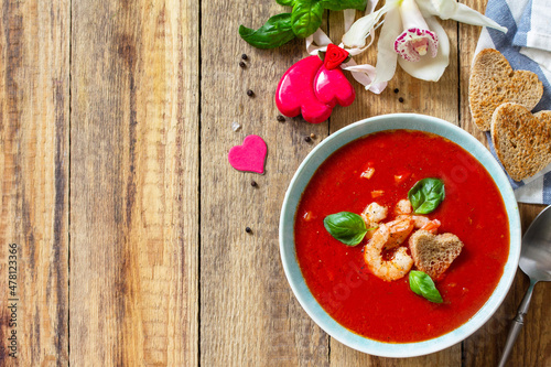 Homemade Valentine soup, festive food. Tomato soup puree gazpacho with tomatoes served seafood on a rustic wooden table. Top view flat lay. Copy space.