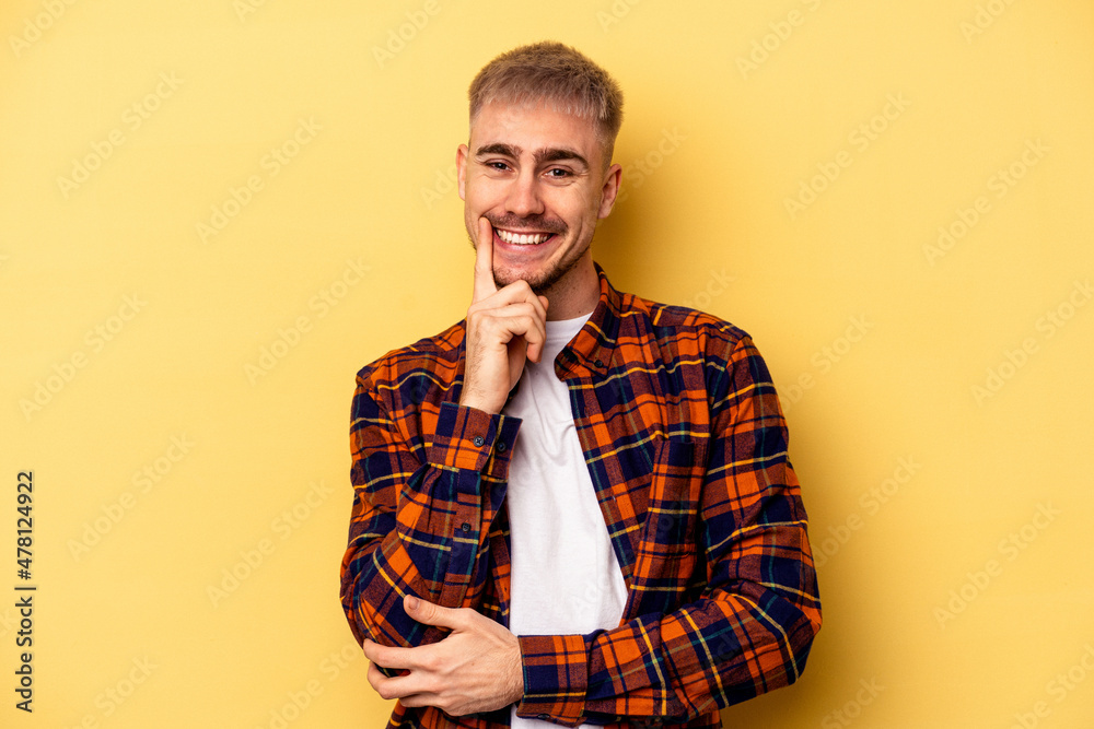Young caucasian man isolated on yellow background smiling happy and confident, touching chin with hand. Young caucasian man isolated on yellow background smiling happy and confident, touching chin with hand.