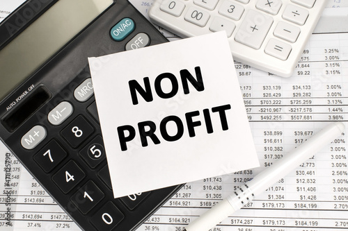 non-profit is written on a white plate that lies on a calculator with a financial document.