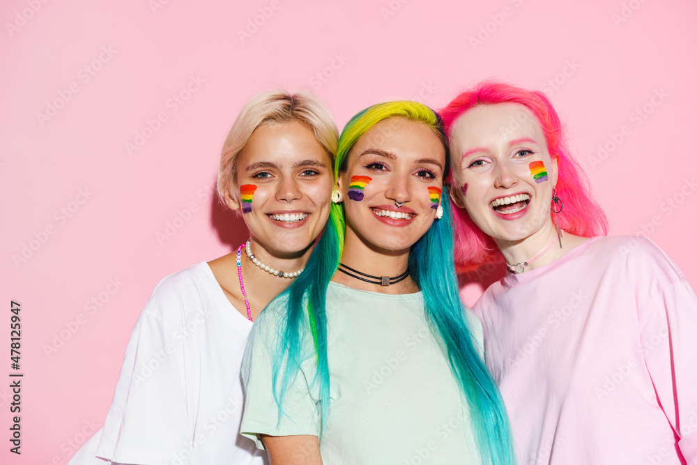 Young three women with rainbow makeup smiling and looking at camera