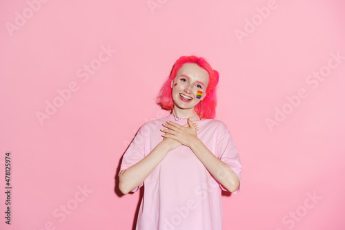 Young woman with rainbow makeup holding hands on her chest © Drobot Dean