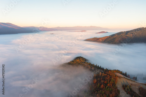 Thick layer of fog covering mountains with colorful trees