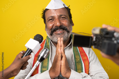 Political person greeting or doing namaste to people through media by looking camera - Concept of interviewing politician or announcement about political news. photo