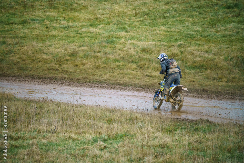 a motorcyclist riding his motorbike across a water-logged muddy track a motorcyclist riding his motorbike across a water-logged muddy track