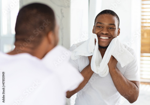 Male Beauty Care. Smiling African American Man Wiping Face With Towel In Bathroom