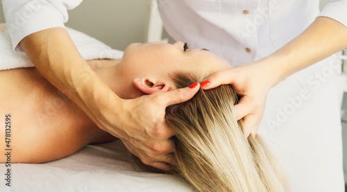 Beautician cosmetologist makes a relaxing head and hair massage professional procedure in a beauty clinic salon for client. Spa health and self-care concept.