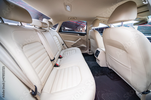 Car interior luxury. Beige comfortable seats, steering wheel, dashboard, climate control, speedometer, display, wood decoration light © Iryna