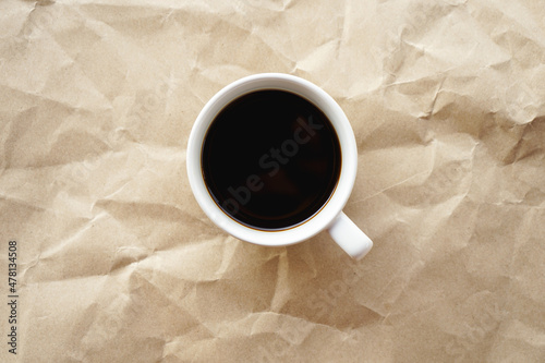 Flat lay view of black coffee cup on crumple brown paper
