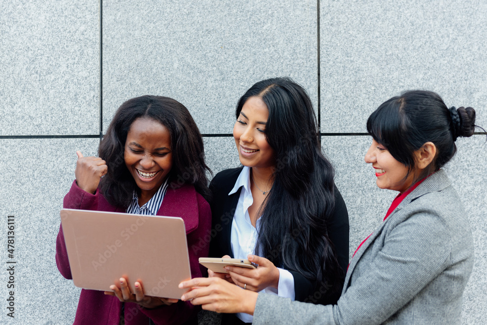Three multiethnic business women consulting their investments and finances on a laptop. Three multiethnic business women consulting their investments and finances on a laptop.