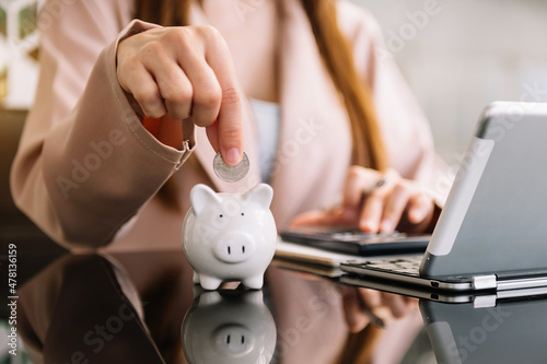 woman hand putting coin into piggy bank ..