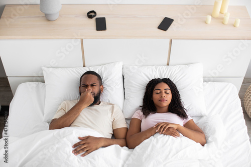 Billede på lærred Sad disgruntled millennial african american husband closes nose from bad scent,