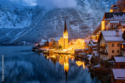 Closeup view of the famous village of Hallstatt  Austria  during winter dusk time with snow and warm lights from the houses