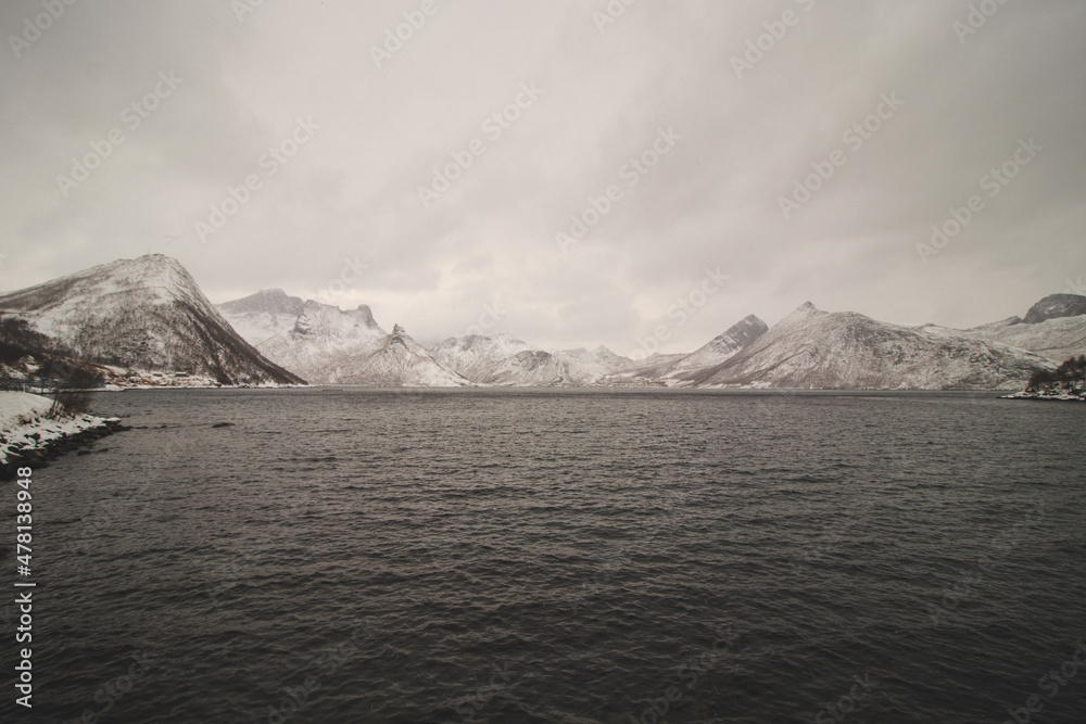 View from the isolated village of Husoy on the island of Senja, Norway. A very lonely fishing village. A view of the stormy Norwegian sea and snow-capped hills beyond the North Pole