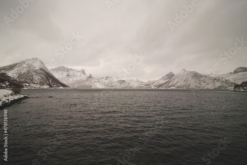View from the isolated village of Husoy on the island of Senja, Norway. A very lonely fishing village. A view of the stormy Norwegian sea and snow-capped hills beyond the North Pole