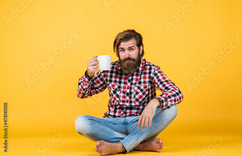 handsome bearded guy with unshaven face and stylish hairdo wear casual clothes drink coffee, cheers © be free