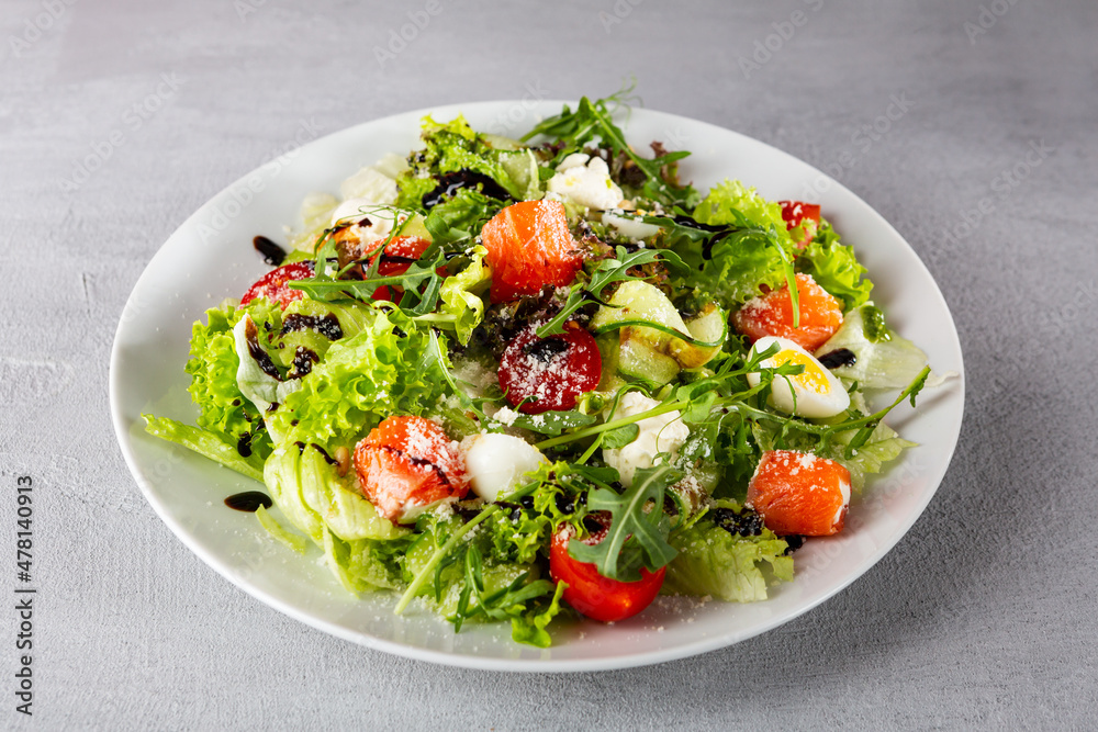 Close up of fresh salad with salmon slices and cheese on white plate Close up of fresh salad with salmon slices and cheese on white plate