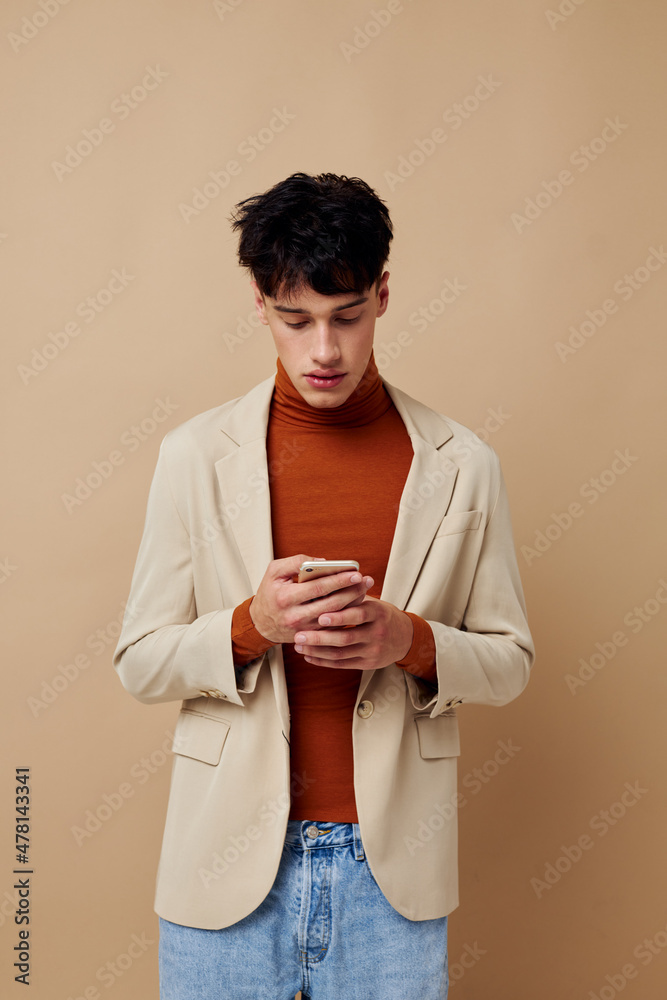 portrait of a young man in a beige jacket talking on the phone light background unaltered portrait of a young man in a beige jacket talking on the phone light background unaltered