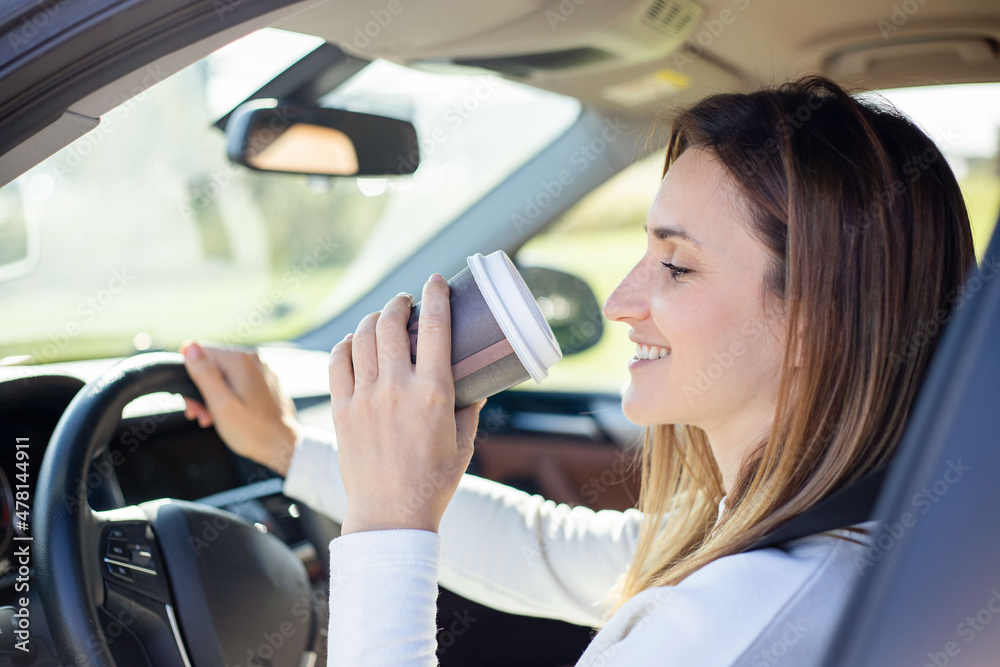 Woman driving and holding a coffee cup.