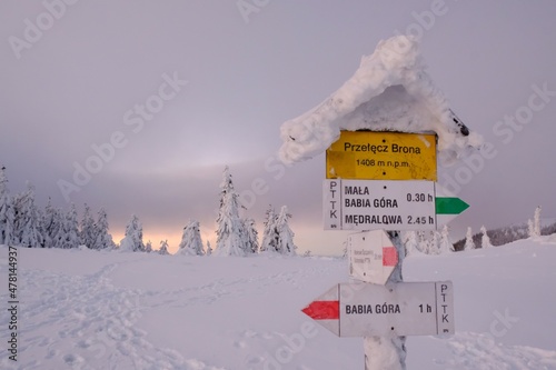 Tourist signpost on Brona Mountain Pass. During winter trek to Babia Gora Mountain in winter scenery at sunrise light. Diablak, Beskid Zywiecki, Poland photo