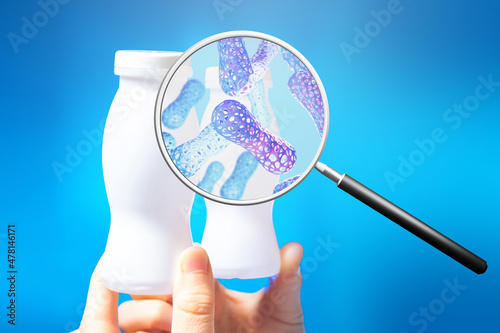 Probiotic yogurt. Magnifying glass with probiotic molecules. Jars with probiotic yogurt on blue. Concept of fermented milk products with beneficial microorganisms. Microbiome research.