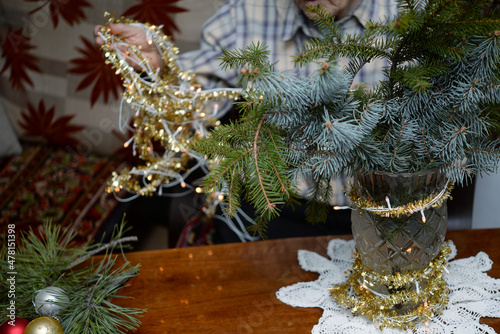 man decorating christmas bouquet with golden garaland photo