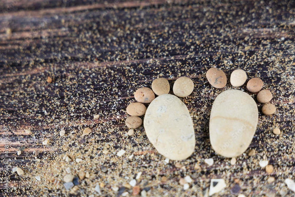 Funny human footprints from stones on a wooden background. Funny human footprints from stones on a wooden background.