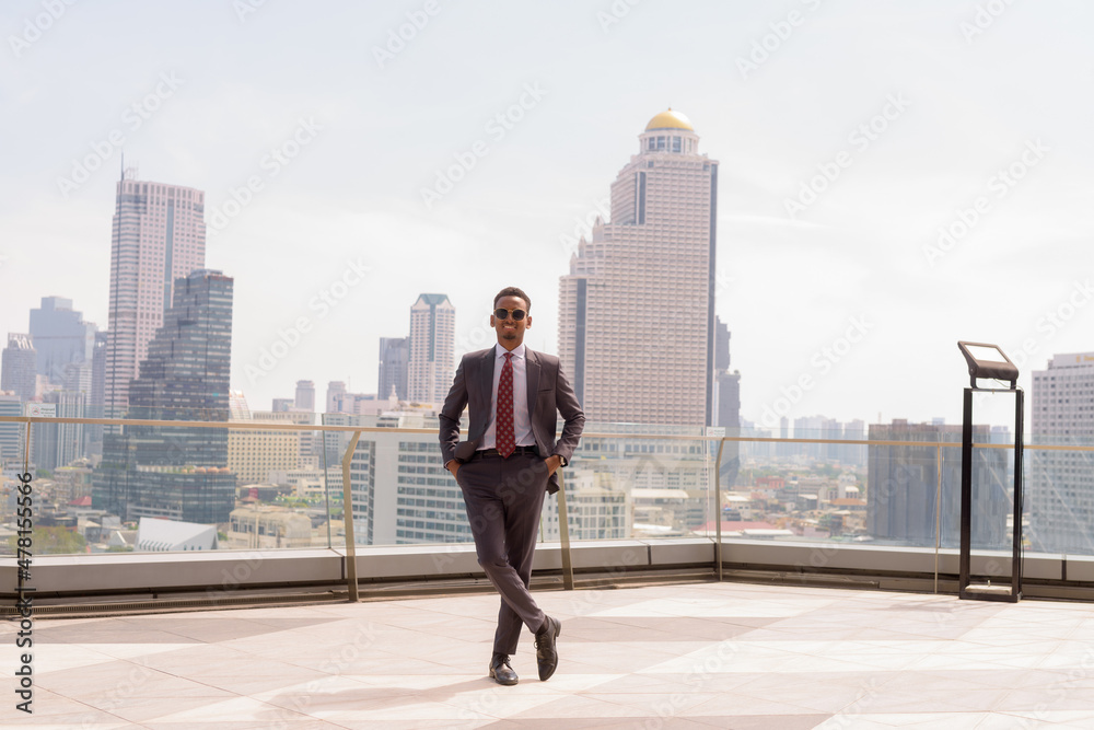 Full length portrait of African businessman wearing suit and tie outdoors in city while standing Full length portrait of African businessman wearing suit and tie outdoors in city while standing
