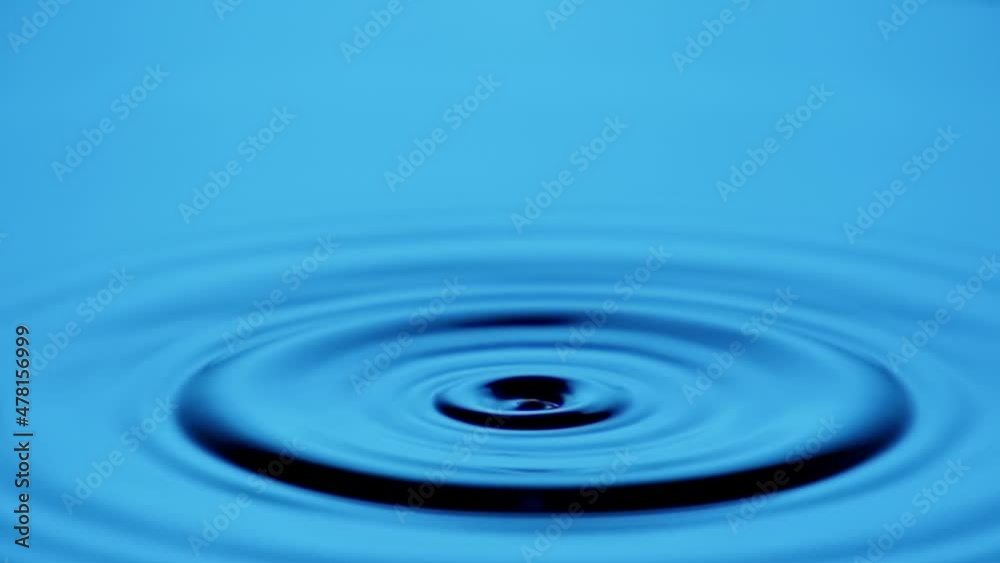 A single drop of water falling into a pool of water in slow motion.