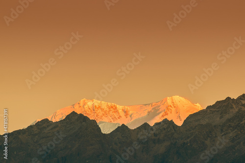 Beautiful first light from sunrise on Mount Kanchenjugha, Himalayan mountain range, Sikkim, India. Orange tint on the mountains at dawn