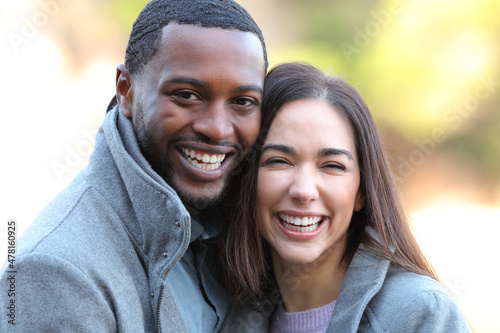 Happy interracial couple laughing at camera in winter