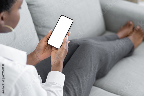 Phone leisure. Online blog. App advertisement. Mobile mockup. Unrecognizable woman browsing internet on smartphone blank screen copy space on couch at home.