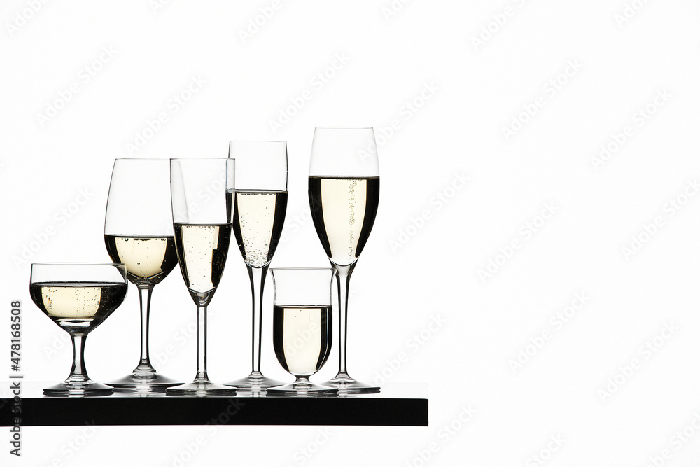 Different filled Champagne glasses on shelf in studio on white background. Different filled Champagne glasses on shelf in studio on white background.