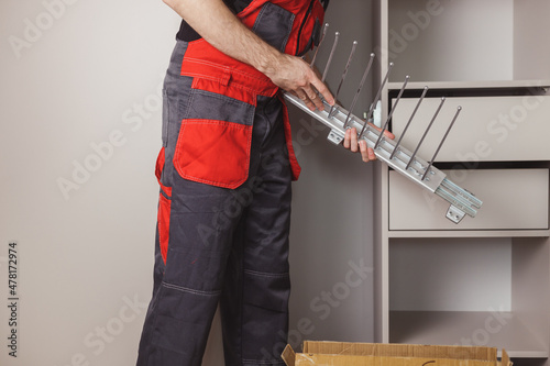 Furniture assembler going to fix sliding pants hanger in wardrobe