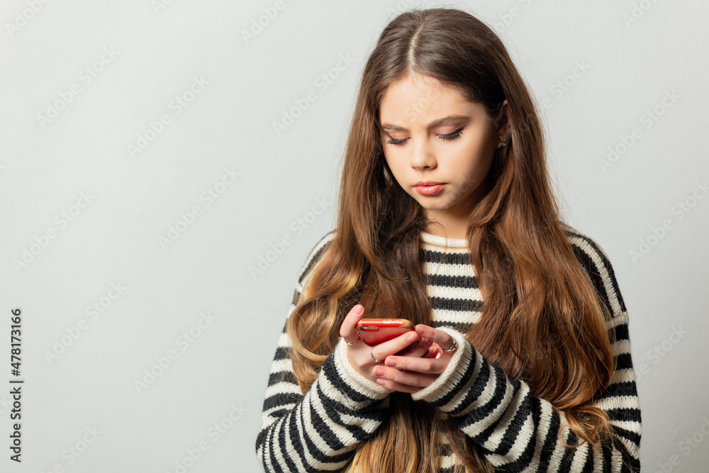 Beautiful girl in striped sweater texting a message on her mobile phone Beautiful girl in striped sweater texting a message on her mobile phone