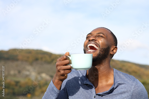 Happy man with black skin laughing drinking coffee