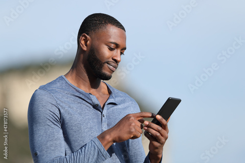 Man with black skin using smart phone in mountain