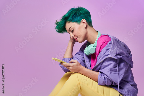Millennial woman with headphones browsing smartphone photo