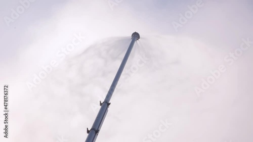 Snow lance (one of type artificial snow machine, cannon or gun) making snow for piste. Climate control for ski resort, artificial spray on a mountains. Making snow with a cannon.