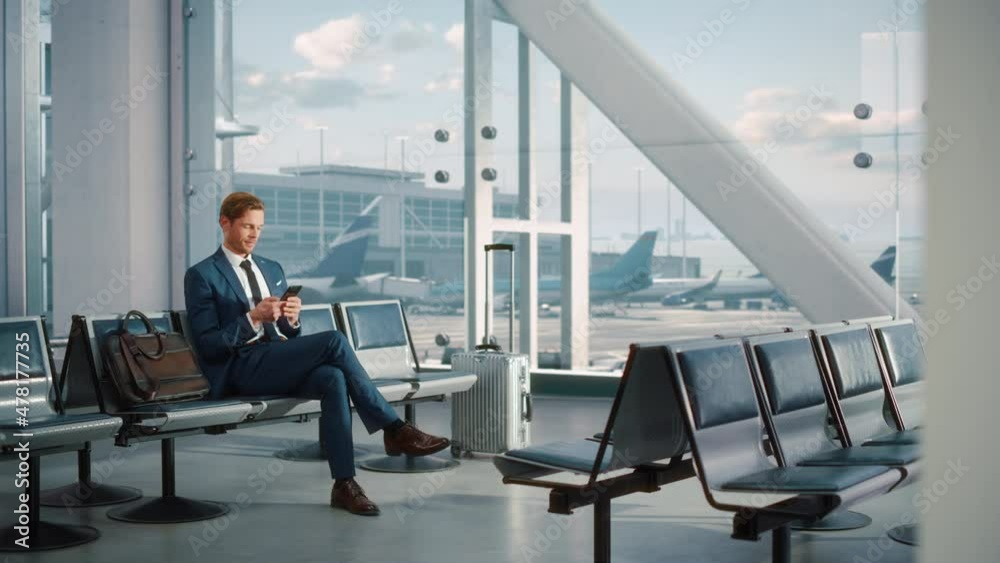 Airport Terminal: Businessman Uses Smartphone, Waiting for a Flight, Doing e-Business e-Commerce Analysis. Traveling Entrepreneur Remote Work Online on Mobile Phone in Boarding Lounge of Airline Hub Airport Terminal: Businessman Uses Smartphone, Waiting for a Flight, Doing e-Business e-Commerce Analysis. Traveling Entrepreneur Remote Work Online on Mobile Phone in Boarding Lounge of Airline Hub