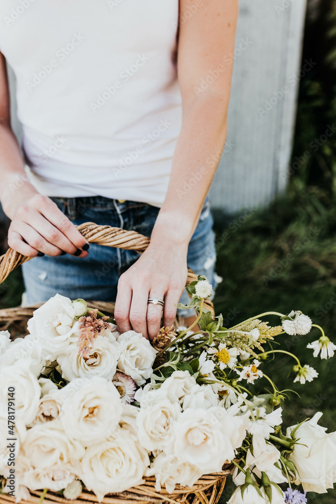 Close up of Woman reaching into basket of fresh picked flowers Close up of Woman reaching into basket of fresh picked flowers