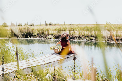 Black woman sits on dock while gazing off to the side