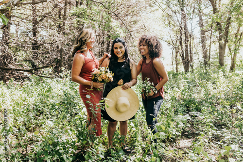 Group of women laughing in a forest surrounded by plants