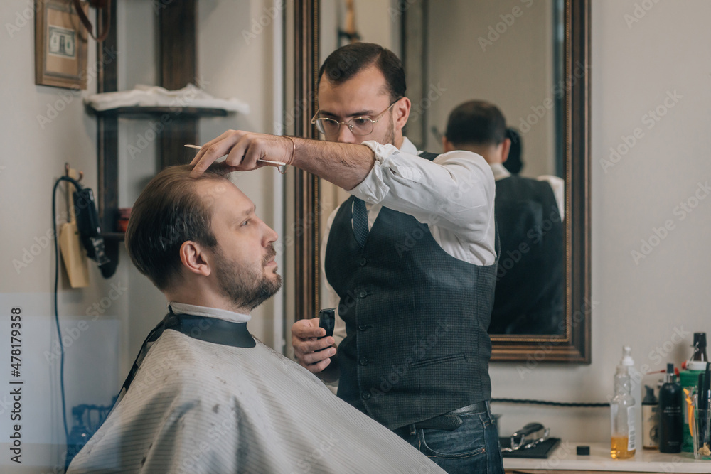 View through window, hairdresser barber cuts hair with scissors. View through window, hairdresser barber cuts hair with scissors.