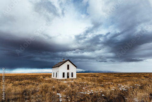 storm clouds loom over white abandoned house in desert, Colorado