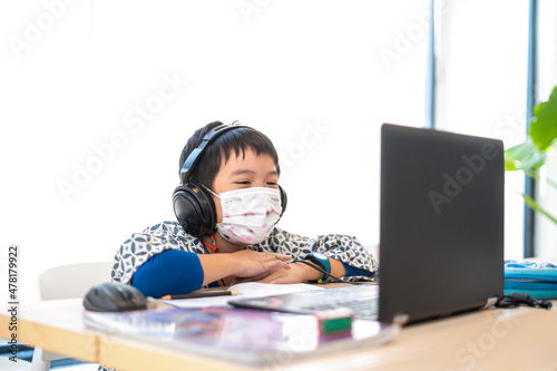Asian boy happy using Laptop computer studying online during home quarantine epidemic problem,chat via computer. homeschooling, online study, online learning, corona virus or technology concept