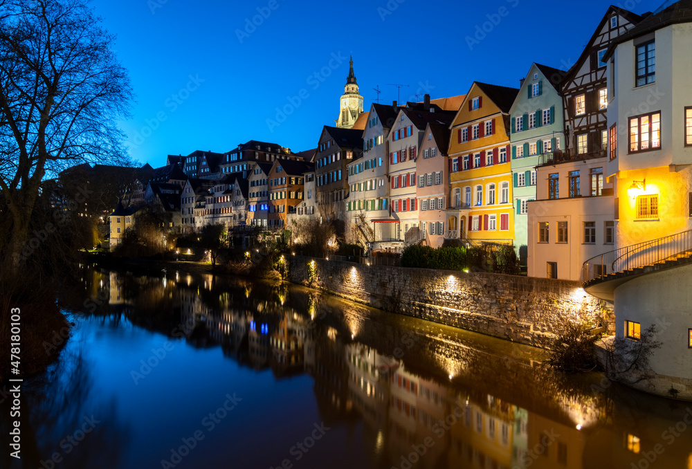 “Neckarfront“ illuminated historic facades of old town of Tuebingen on Neckar River in southern Germany an a winter evening with colorful reflections, Hölderlin Tower and Church.