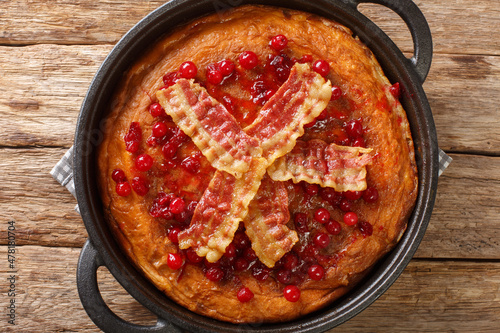 Swedish egg pancake with crispy bacon and cranberries close-up in a frying pan on the table. horizontal top view from above photo