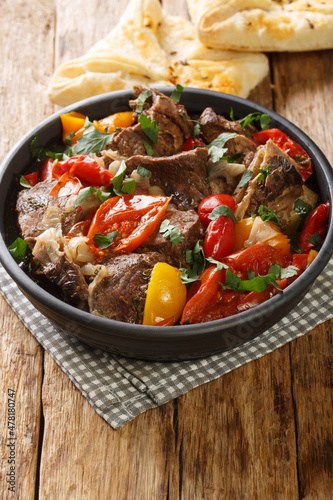 Caucasian cuisine Buglama lamb stewed with vegetables and herbs close-up in a bowl on a wooden table. vertical photo